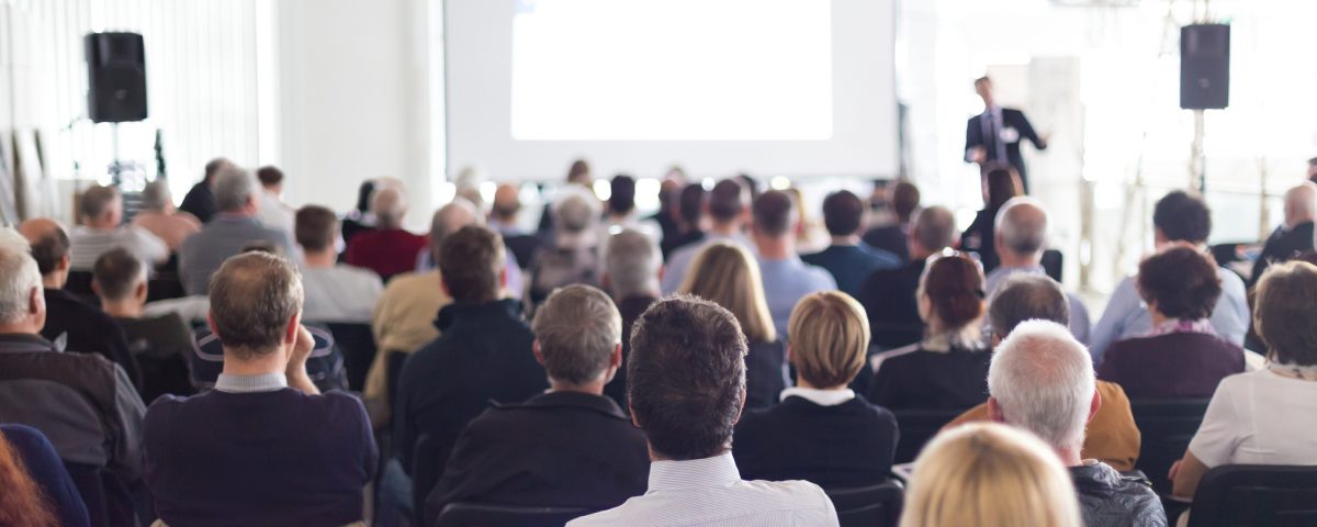 Speaker Giving a Talk at Business Meeting. Audience in the conference hall. Business and Entrepreneurship. Panoramic composition suitable for banners.